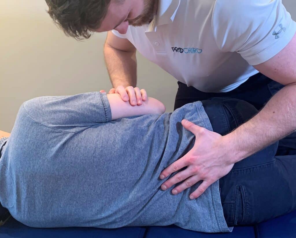 Josh French, Surrey chiropractor and clinical director of Pro Chiro spine and Sports Chiropractic, performing a spinal adjustment on a patient with low back pain.